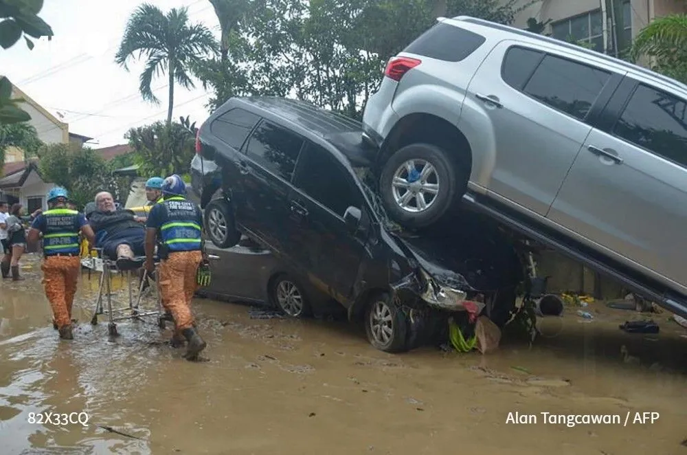 Rescatistas evacúan a un hombre en camilla en medio de las inundaciones provocadas por el tifón Kalmaegi en Cebu City, Filipinas; vehículos apilados muestran la fuerza del agua